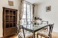 dining area highlighted by a glass table with 4 matching seats in a Paris luxury apartment