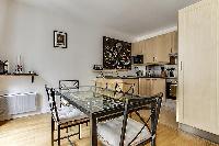 dining area highlighted by a glass table with 4 matching seats in a Paris luxury apartment