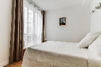 cozy bedroom with queen-sized beds, ample closet space, and drawers in a Paris luxury apartment