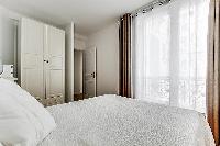cozy bedroom with queen-sized beds, ample closet space, and drawers in a Paris luxury apartment