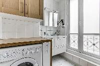full bathroom with a washing machine, dryer, and double sink in a Paris luxury apartment