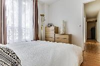 cozy bedroom with queen-sized beds, ample closet space, and drawers in a Paris luxury apartment