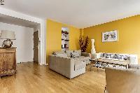 cozy living room with rich yellow walls, two Scandinavian-style double-sized sofa beds, and entertai