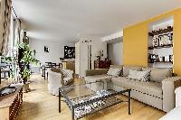 cozy living room with rich yellow walls, two Scandinavian-style double-sized sofa beds, and entertai