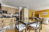 dining area highlighted by a glass table with 4 matching seats in a Paris luxury apartment