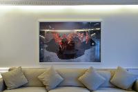 a long taupe sofa with pillows, and a work of art hanged on a white wall in paris luxury apartment