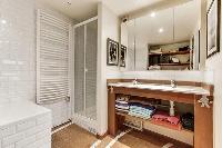 spacious well-maintained and neat bathroom with bathtub, shower and sinks in a 4-bedroom Paris luxur
