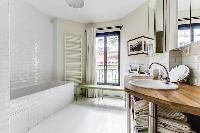 spacious well-maintained and neat bathroom with bathtub and sinks in a 4-bedroom Paris luxury apartm