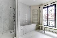 spacious well-maintained and neat bathroom with bathtub and shower in a 4-bedroom Paris luxury apart