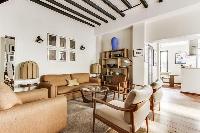 a lovely open living with a leather sofa, arm chairs, a centerpiece, a lovely carpet on a parquet fl