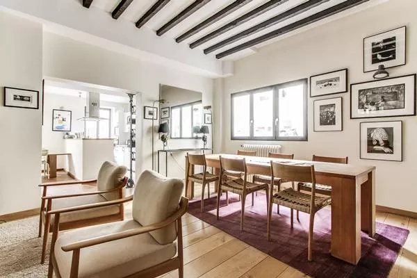 a lovely living and dining area with exposed wooden beams in a 4-bedroom Paris luxury apartment